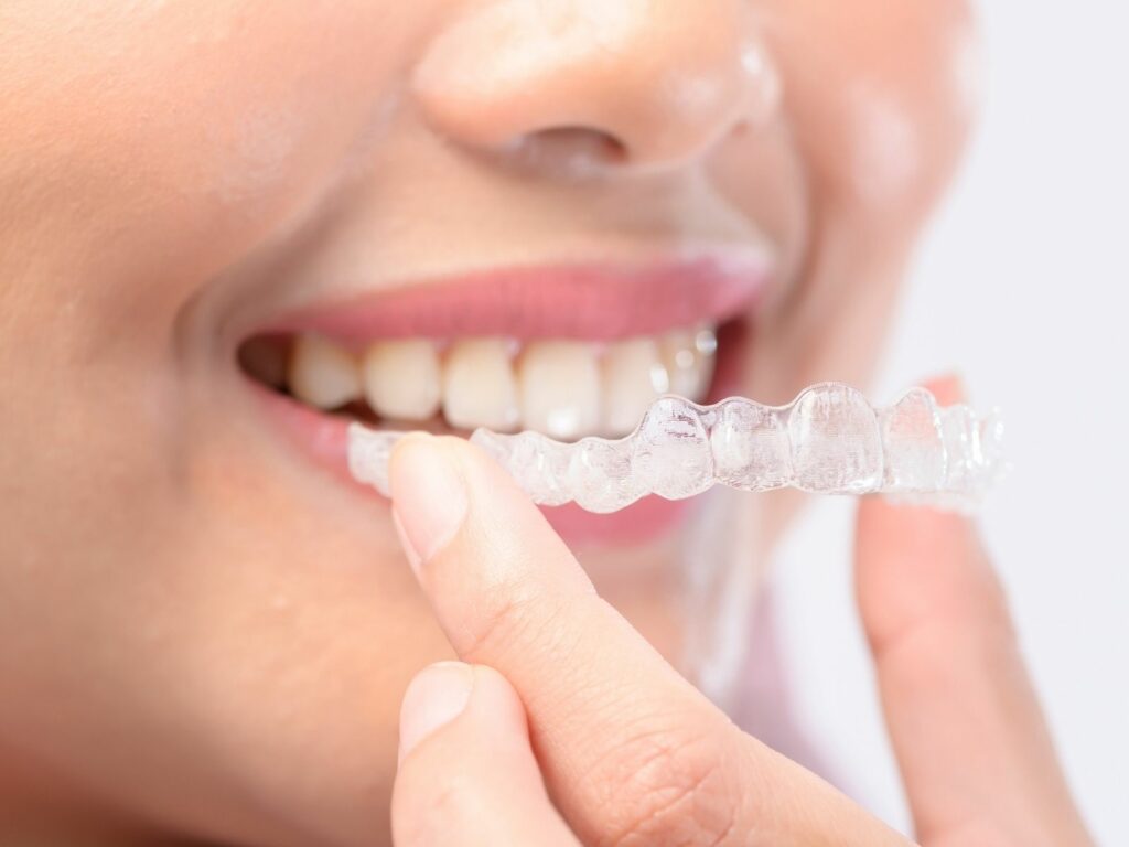 Jeune femme souriante tenant des aligneurs Invisalign